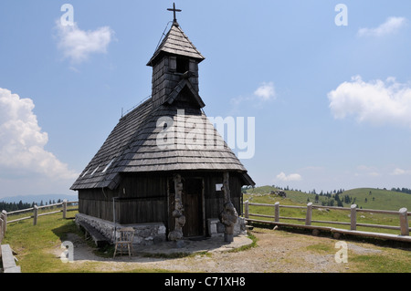 Legno Snezna Marija cappella con pine ghiaia tetto sul pascolo a 1600m Velika planina altopiano, Kamnik-Savinja Alpi, Slovenia Foto Stock