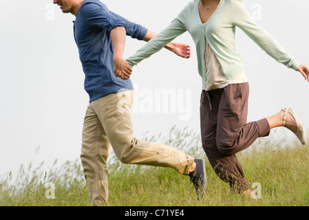 Giovane holding hands in esecuzione sul prato, ritagliato Foto Stock
