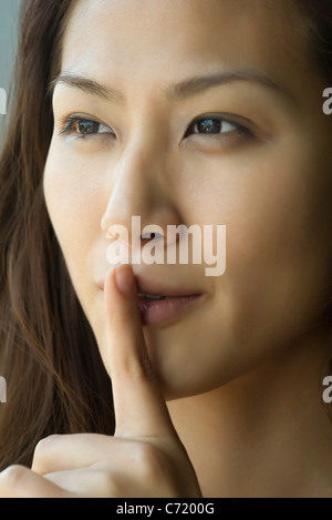 Giovane donna con il dito sulle labbra Foto Stock