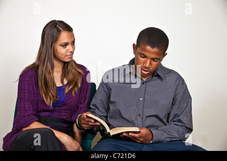 Multi etnico americano africano ragazzo e ragazza ispanica leggere e ascoltare insieme la Bibbia.14-18 anni vecchio signor © Myrleen Pearson Foto Stock