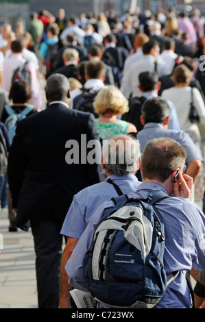 Scena di strada di persone pendolari su London Bridge schienali di uomini & donne lavoratori ufficio a piedi per la stazione di London Bridge sunny sera Rush Hour England Regno Unito