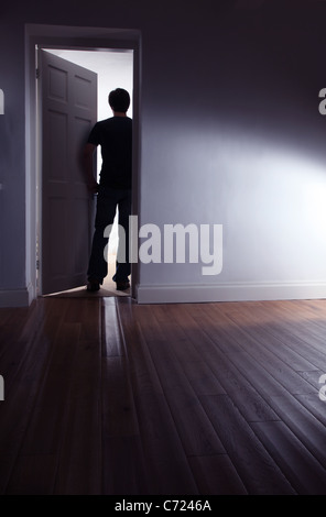 Vista posteriore di un oscuro maschio a piedi di una camera oscura. Foto Stock