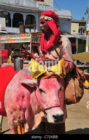 L'uomo con la vacca sacra in città Foto Stock