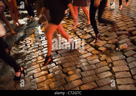 Fashionistas manovrare le strade lastricate in loro designer di calzature nel trendy Meatpacking District di New York Foto Stock