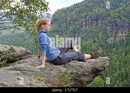 Donna seduta su rocce e guardando in lontananza, Svizzera Sassone Elbe montagne di arenaria, Sassonia, Germania, Europa Foto Stock