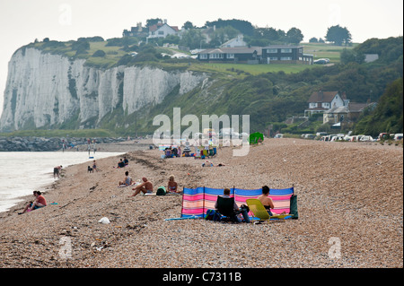 La gente seduta sulla spiaggia di ciottoli a Kingsdown nel Kent Foto Stock