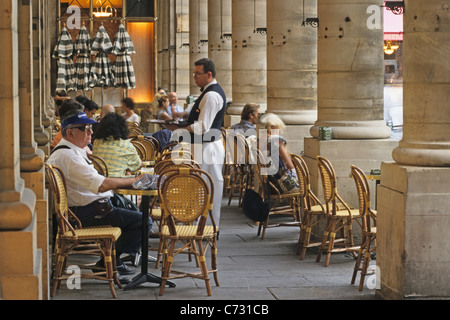 Persone in Cafe, il cameriere che servono bevande Cafe le Nemours, Place Colette, 1. Arrondissement di Parigi, Francia Foto Stock