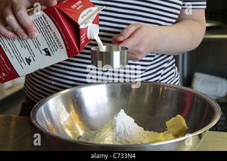 Una persona versando il latte e la preparazione per fare un po' di lievito. Foto Stock
