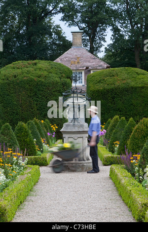 Giardiniere spingendo una carriola in i giardini del castello di siepi tagliate nel parco del castello di Clemenswerth Castello Inferiore Soegel Foto Stock