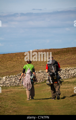 Arrampicatori a piedi con le loro attrezzature per fare un po' di arrampicata su roccia a Devil's scorrere su Lundy Island, Devon, Inghilterra Regno Unito nel mese di agosto Foto Stock