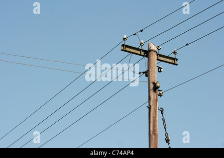 In legno antico pilastro elettrico contro il cielo blu chiaro Foto Stock