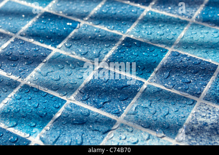 Piastrelle blu in piscina con gocce d'acqua in presenza di luce solare Foto Stock