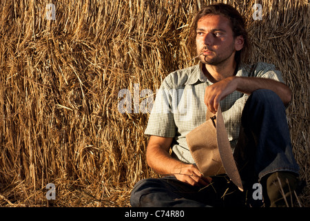 Cowboy con balle di fieno seduto a terra Foto Stock