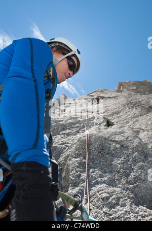 Un belayer belaying il suo partner di arrampicata sul granito di Pyramide du Tacul, Chamonix Mont Blanc. Foto Stock