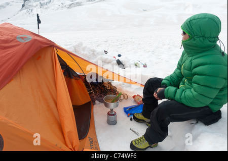 Un uomo la cottura la sua colazione con la sua tenda sul Vallee Blanche ghiacciaio in Chamonix, Francia. Foto Stock