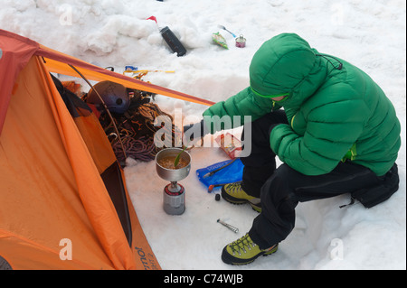 Un uomo la cottura la sua colazione con la sua tenda sul Vallee Blanche ghiacciaio in Chamonix, Francia. Foto Stock