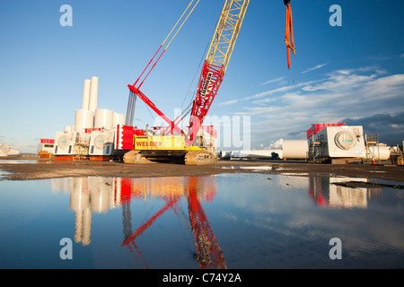 Turbina eolica le parti destinate alla Walneyoffshore wind farm, che si riflette in una pozzanghera sulla banchina a Mostyn. Foto Stock