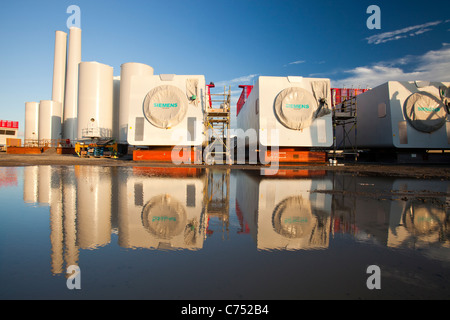 Turbina eolica le parti destinate alla Walneyoffshore wind farm, che si riflette in una pozzanghera sulla banchina a Mostyn. Foto Stock