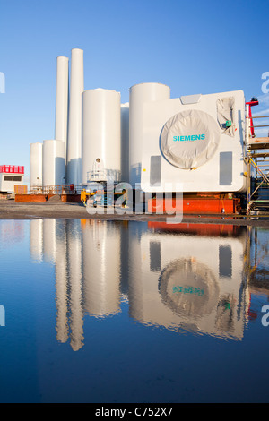 Turbina eolica le parti destinate alla Walneyoffshore wind farm, che si riflette in una pozzanghera sulla banchina a Mostyn. Foto Stock