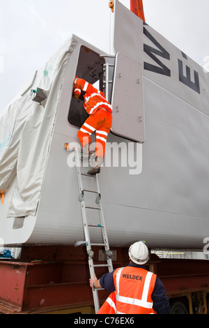 Preparare i lavoratori per il sollevamento di una navicella di una turbina eolica su un martinetto fino barge per il Walney offshore wind farm. Foto Stock