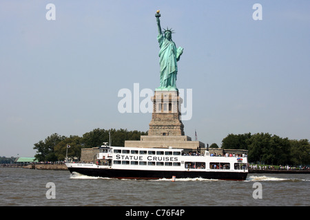 Un tour in barca passa davanti alla statua della libertà nel porto di New York. Foto Stock