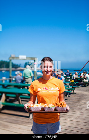 Un server può contenere un piatto di frutti di mare su una dock in un pomeriggio soleggiato. Foto Stock