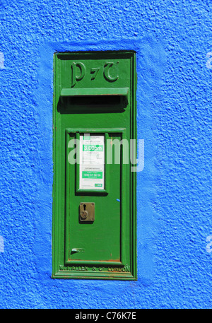 Un dipinto luminosamente muro di casa ospita un servizio postale irlandese casella postale, Kenmare, Co Kerry, Rep dell'Irlanda. Foto Stock
