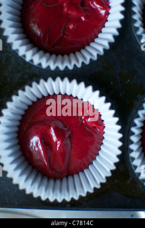 Red Velvet cupcake miscela in casi di carta pronti per la cottura. Foto Stock