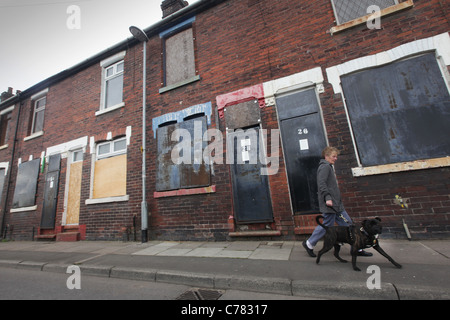 Una donna cammina il suo cane oltre le case imbarcato su Newport middleport Lane Stoke on Trent Foto Stock