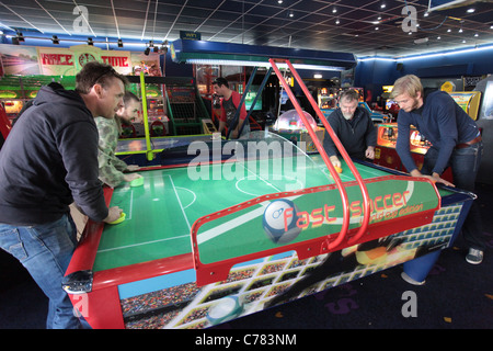 Gli uomini che giocano a air hockey gioco arcade Foto Stock