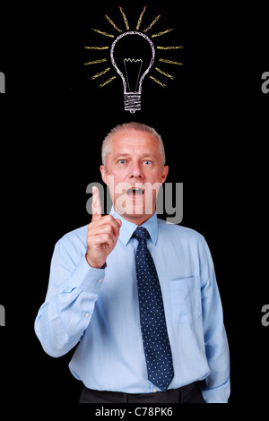Foto di un imprenditore maturo contro uno sfondo nero con un gesso lampadina disegnato sopra la sua testa Foto Stock