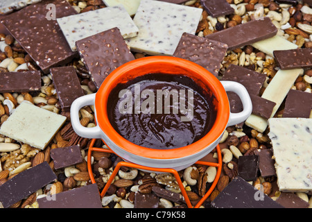 Il cioccolato fuso in una pentola fondue nel mezzo di una catasta di pezzi di cioccolato Foto Stock