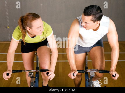 Paio utilizzando le biciclette in un fitness club, guardando ogni altro a prezzi competitivi Foto Stock