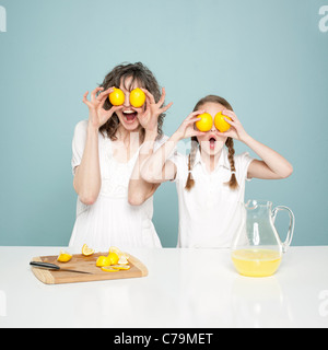 Studio shot di madre e figlia (10-11) tenendo i limoni, ingannare circa Foto Stock