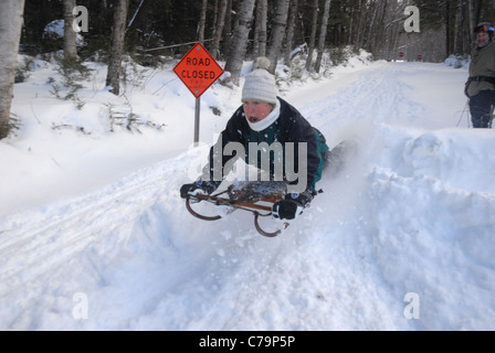 Una donna gli sled sopra una collina come lei gode di inverno nel Vermont. Foto Stock