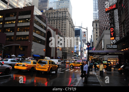 Giallo taxi, riflessi rosso, wet pedoni, grattacieli, pioggia-imbevuta 7th Avenue 52nd Street, verso Times Square, New York Foto Stock