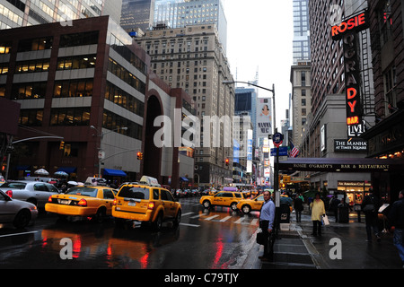 Vista umido giallo taxi, pedoni, riflessi rosso, grattacieli, piovosa 7th Avenue 52nd Street, verso Times Square, New York Foto Stock