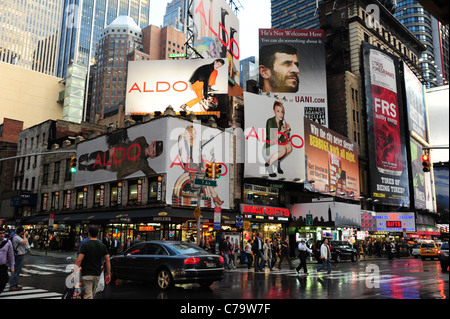 Auto e persone che attraversano la tarmac wet blue neon rosso 7th Avenue, anteriore grattacielo annunci, 48th Street intersezione, New York City Foto Stock