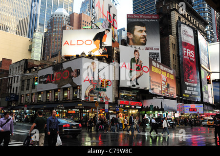 Le persone che attraversano la 7th Avenue asfalto umido rosso neon blu riflessioni grattacielo anteriore inserzioni, angolo West 48th Street, New York City Foto Stock