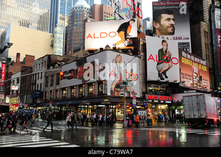 Vista la pioggia le luci al neon, negozi illuminati, persone cartellone pubblicitario, angolo 7° Avenue West 48th Street, New York City, Stati Uniti Foto Stock