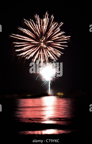 Bellissimi fuochi d'artificio di andare oltre il cielo notturno riflettendo sull'acqua. Foto Stock
