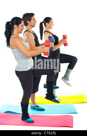 Tre giovani adulti facendo fitness con barbell e piedi su tappeti colorati Foto Stock