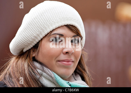 Una giovane e bella donna ispanica con un sorriso sul suo viso indossare una buretta invernale maglia stile hat. Foto Stock