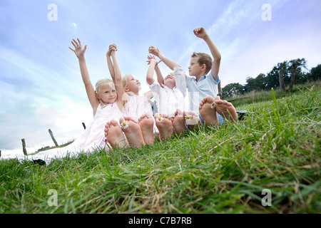 Bambini che giocano e rilassante su un prato in estate a piedi scalzi, Eyendorf, Bassa Sassonia, Germania, Europa Foto Stock