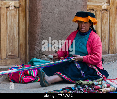 Il quechua donna indiana si intreccia con una fascetta telaio in Cusco, Perù Foto Stock