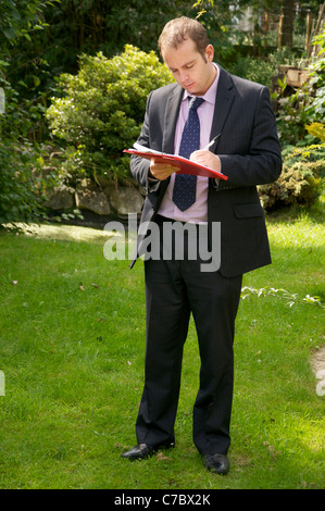 Geometra ispezione esterna della proprietà e prendendo appunti/preparazione di uno schizzo. Foto Stock