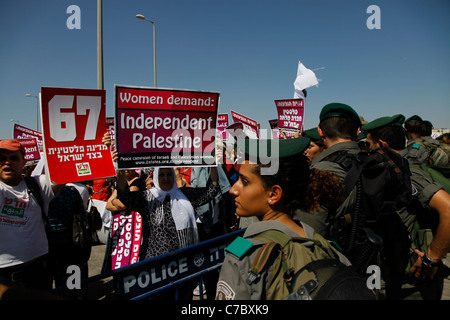 La polizia di frontiera israeliana vigila mentre le donne palestinesi e gli attivisti di pace israeliani prendono parte a una manifestazione contro l'occupazione israeliana dei territori palestinesi a Kalandia o al checkpoint Qalandia tra Gerusalemme e Ramallah in Israele Foto Stock