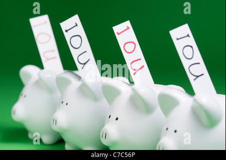 Gruppo di piggy banche con IOU che esce di coin slot Foto Stock