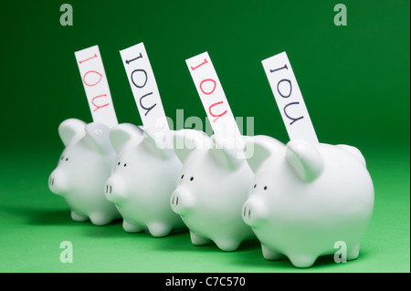 Gruppo di piggy banche con IOU che esce di coin slot Foto Stock