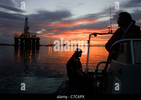 Olio della piattaforma di perforazione, con il sole che sorge dietro di esso, in Cromarty Firth, Scozia nel Regno Unito. Foto Stock